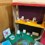 Ein Modell eines Spielhauses aus Pappe mit verschiedenen Möbelstücken und Dekorationen im Inneren.